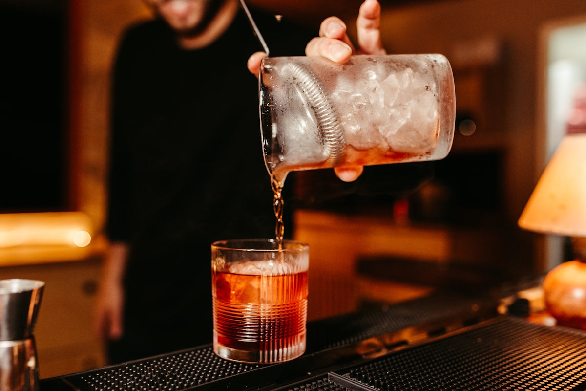 a man pours a drink into a glass