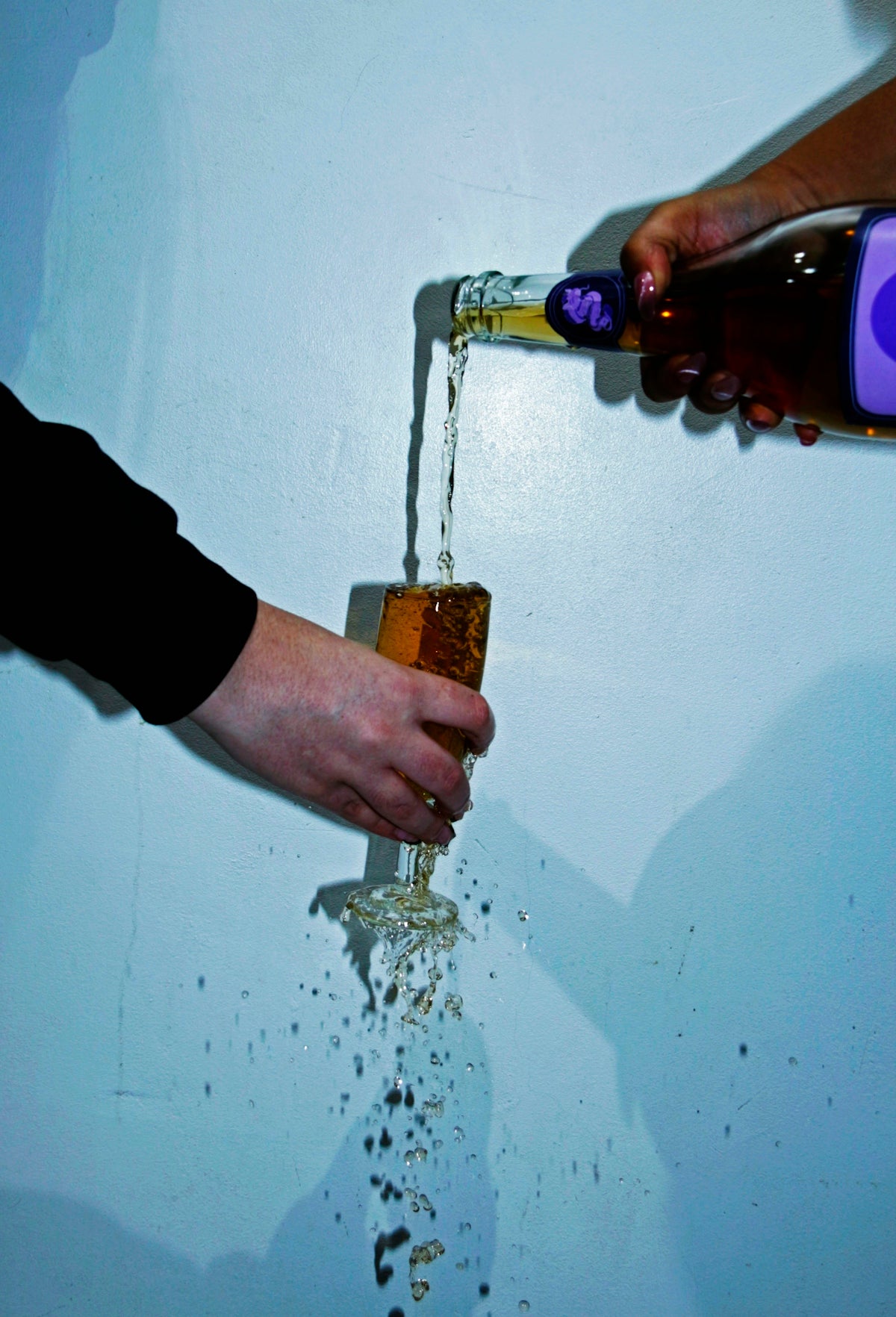 a person pouring a drink into a glass