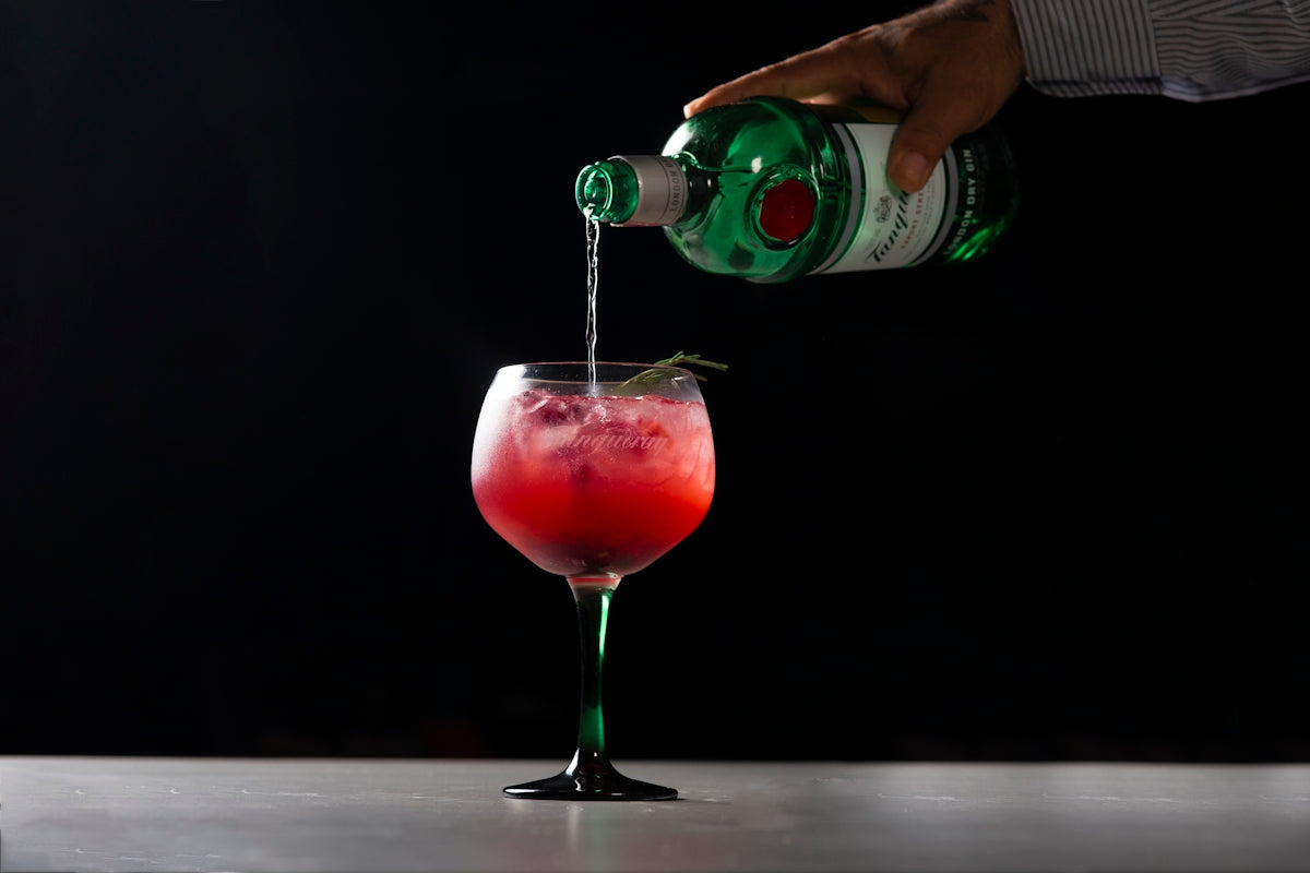 person pouring beverage on wine glass