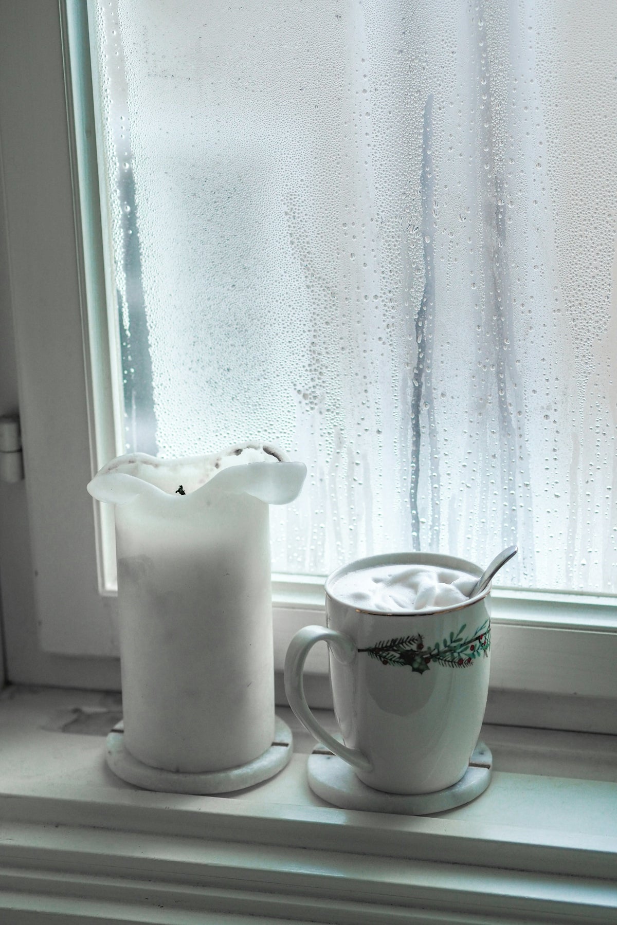 a pitcher of milk next to a cup on a window sill