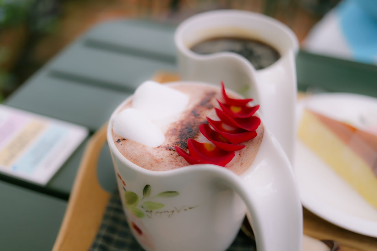 a pitcher of hot chocolate with a flower on it