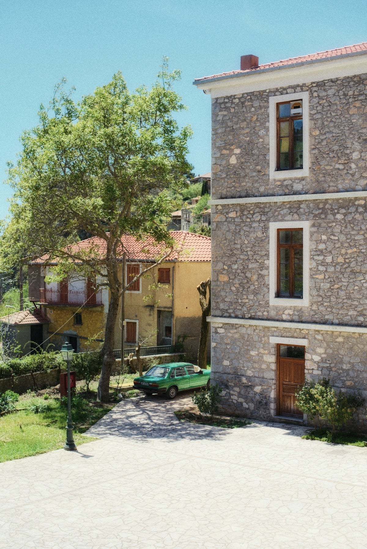 a green car parked in front of a stone building