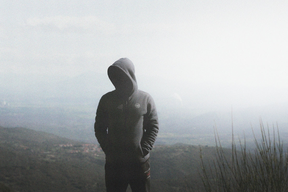 a man in a hoodie standing on top of a mountain