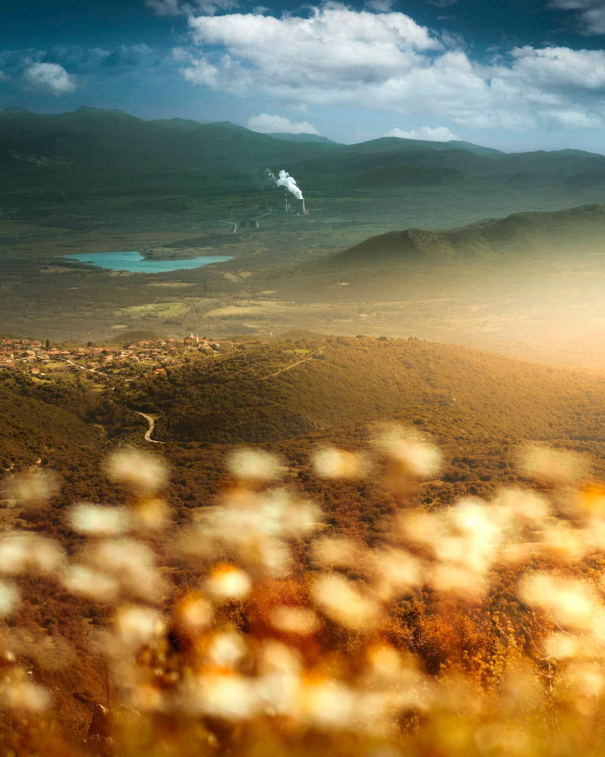 a plane flying over a lush green hillside under a cloudy sky