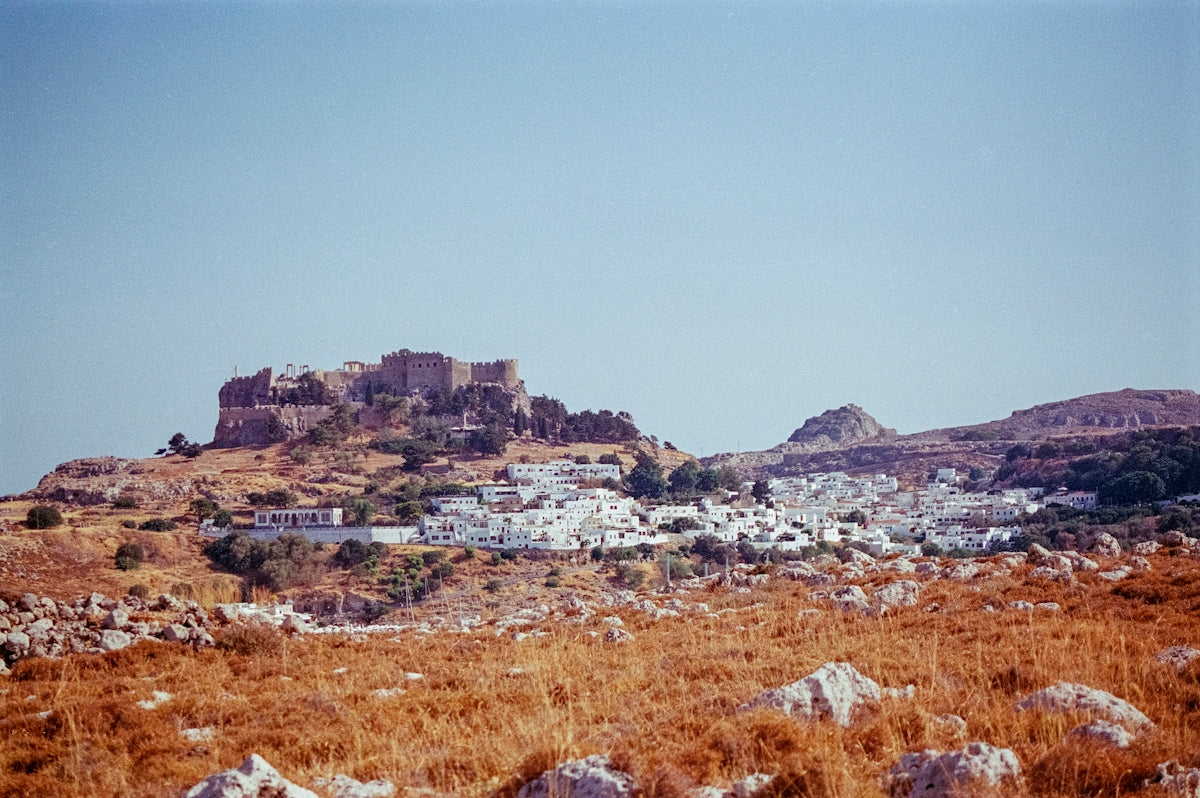 A field with rocks and grass and a hill in the background