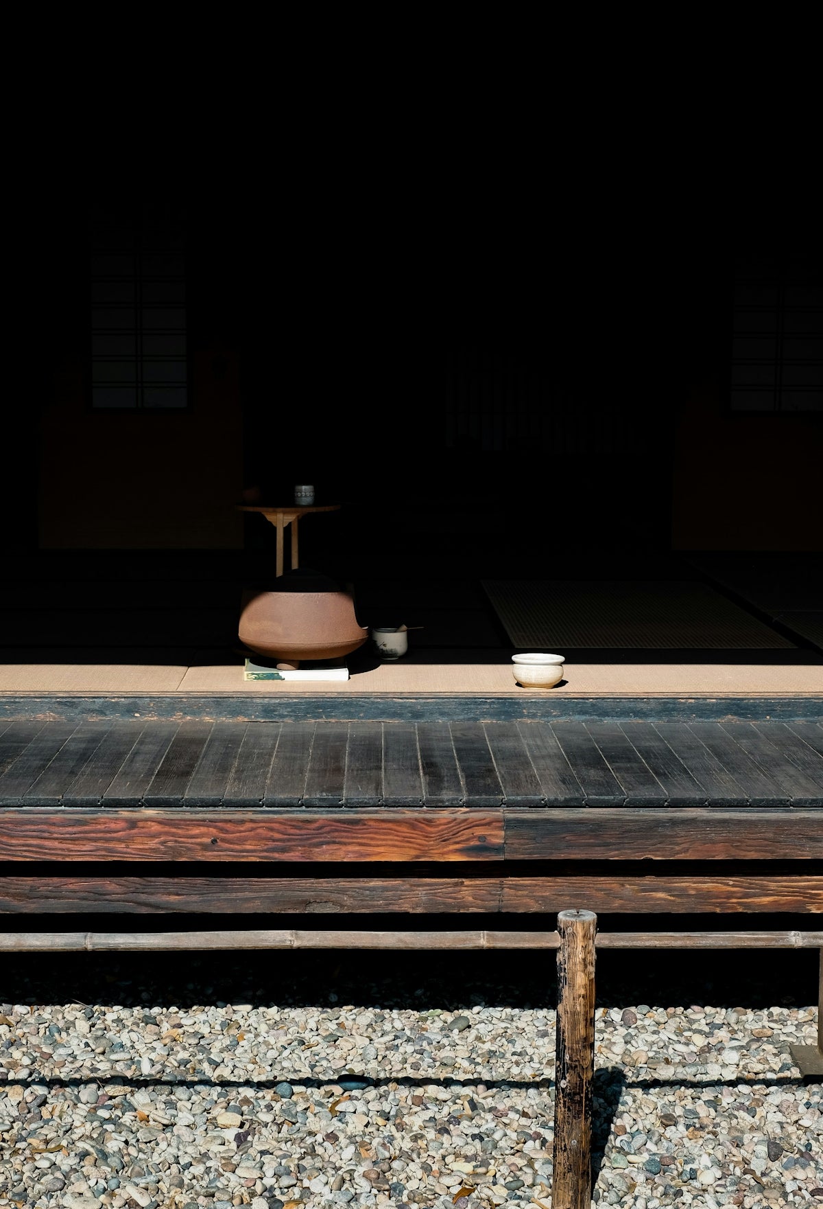 A wooden bench sitting on top of a gravel covered ground