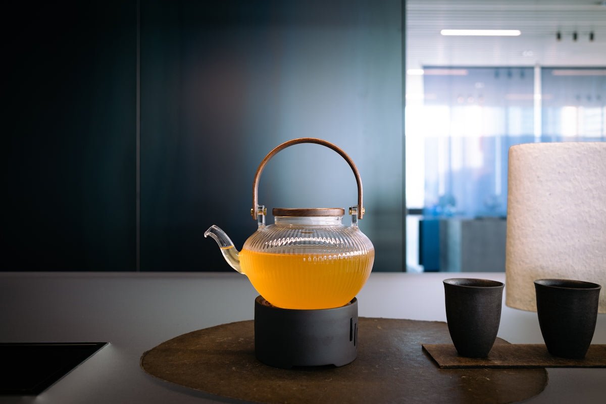 Glass teapot with yellow liquid and two cups