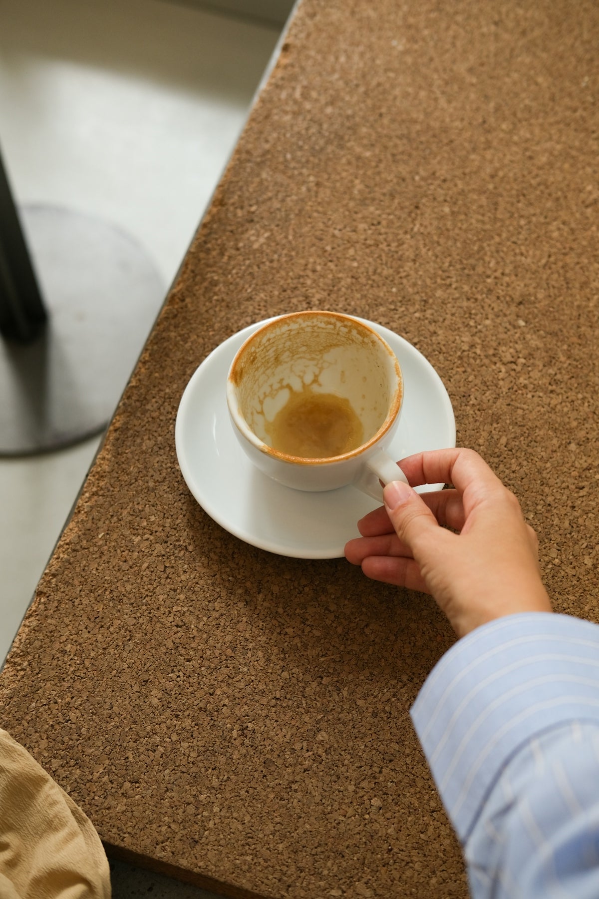 Hand holding an empty coffee cup on a table