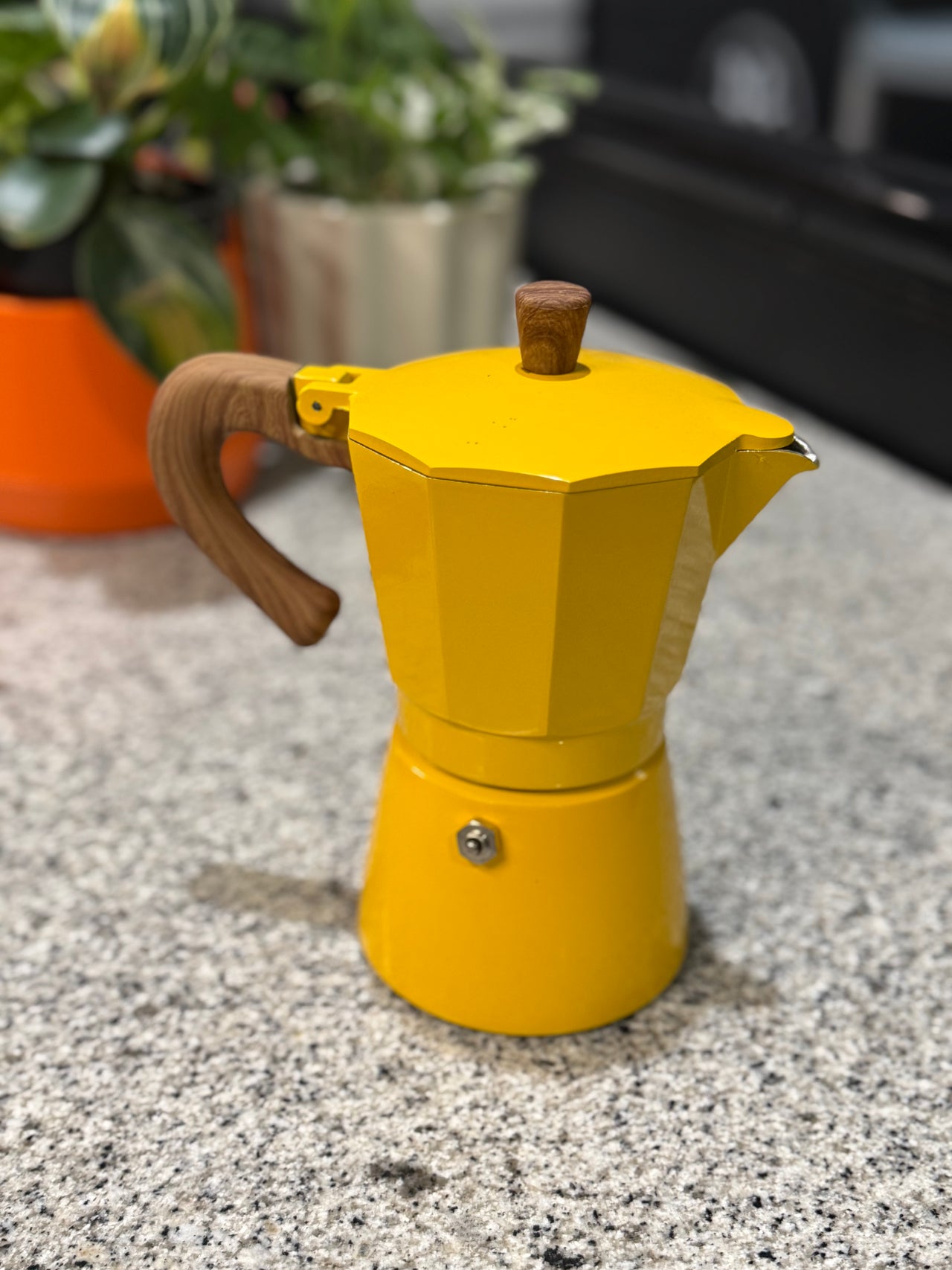 Yellow espresso maker with wooden handle on a speckled surface