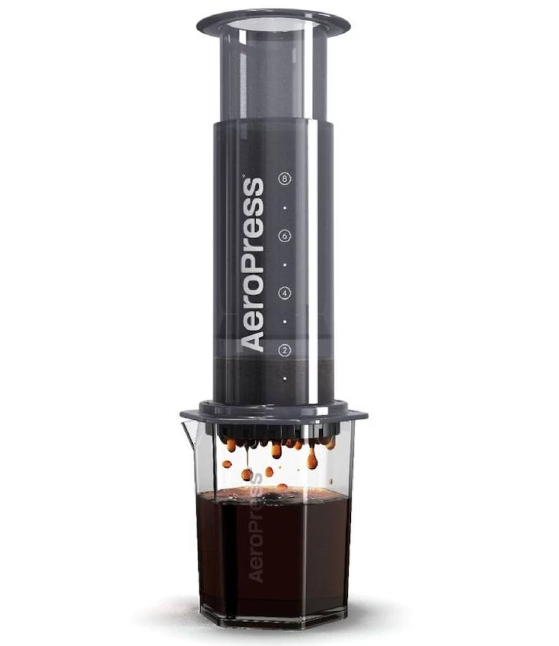 Aeropress coffee maker with coffee dripping into a glass container on a white background