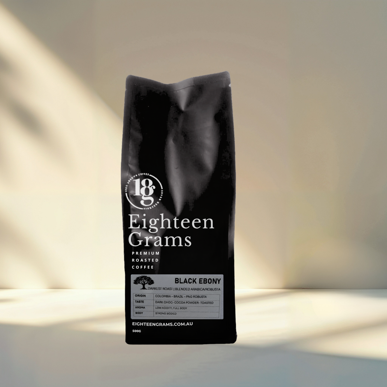 Black coffee bag labeled 'Eighteen Grams' on a light background. Black Ebony coffee beans with a strong roasted profile, heavy body, very low acidity and intense cocoa nib, toasted coffee and bitter dark chocolate flavour.