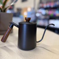 Thumbnail for Black teapot with wooden handle and lid on a light surface