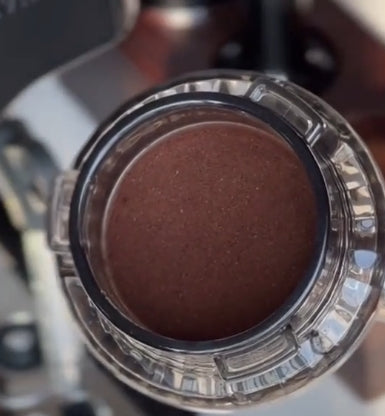 Close-up of a coffee filter with a brown substance inside, likely coffee grounds.