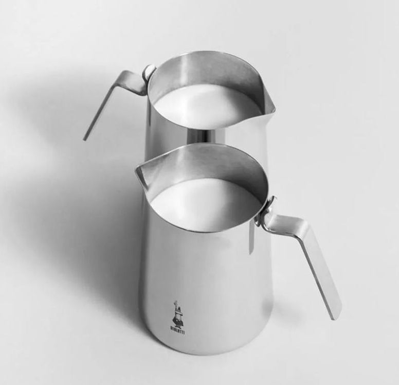 Stainless steel milk frothing pitcher on a light gray background