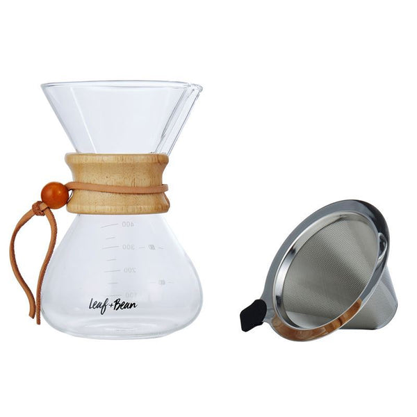 Clear glass coffee maker with wooden collar and brown leather tie, accompanied by a metal filter on a white background.