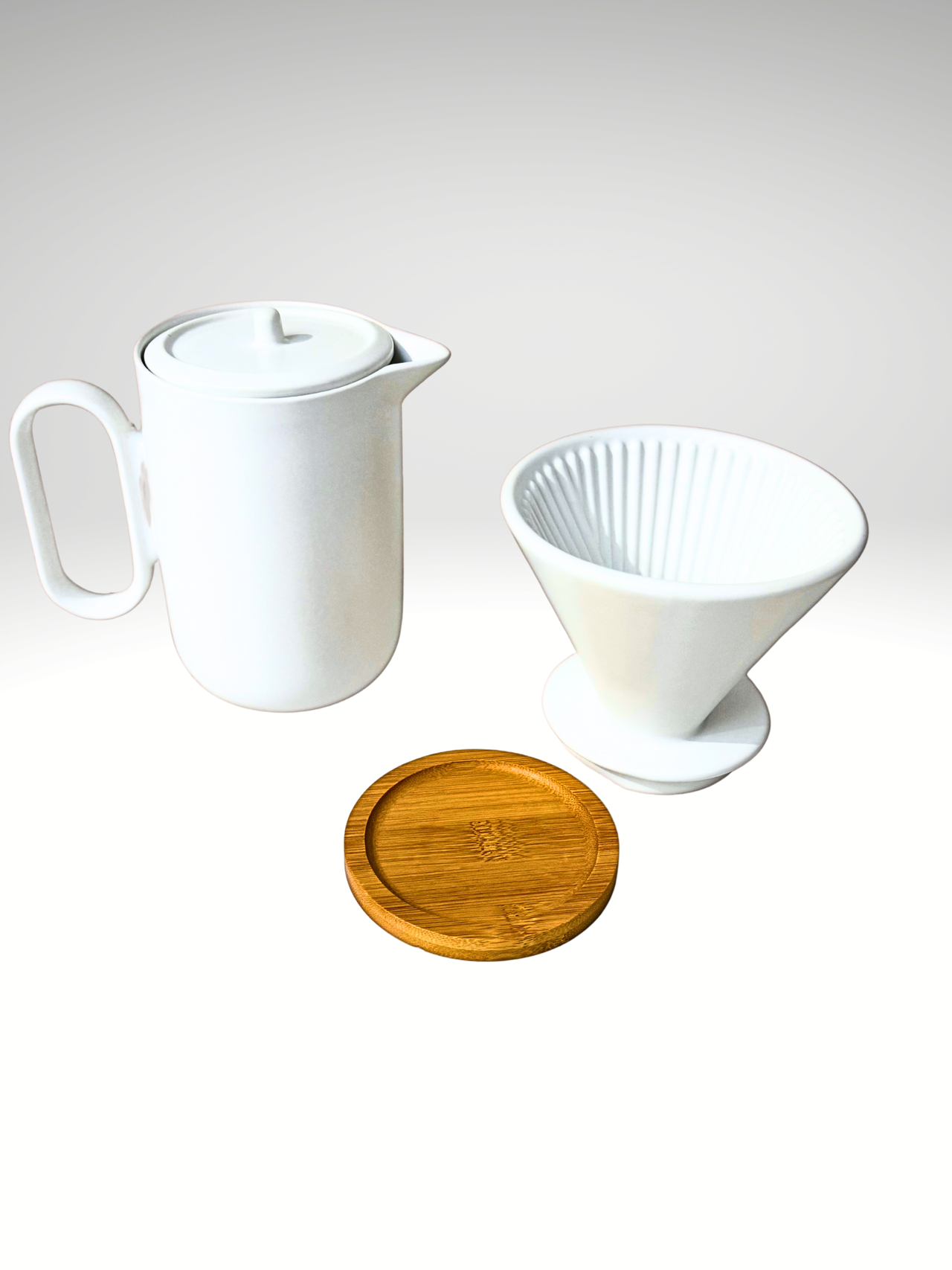 White ceramic teapot, wooden coaster, and white coffee filter on a light gray background
