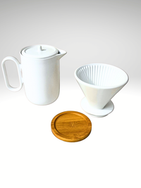 Thumbnail for White ceramic teapot, wooden coaster, and white coffee filter on a light gray background