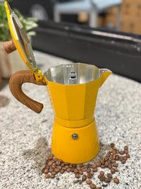 Thumbnail for Yellow espresso maker with wooden handle on a surface with coffee beans around