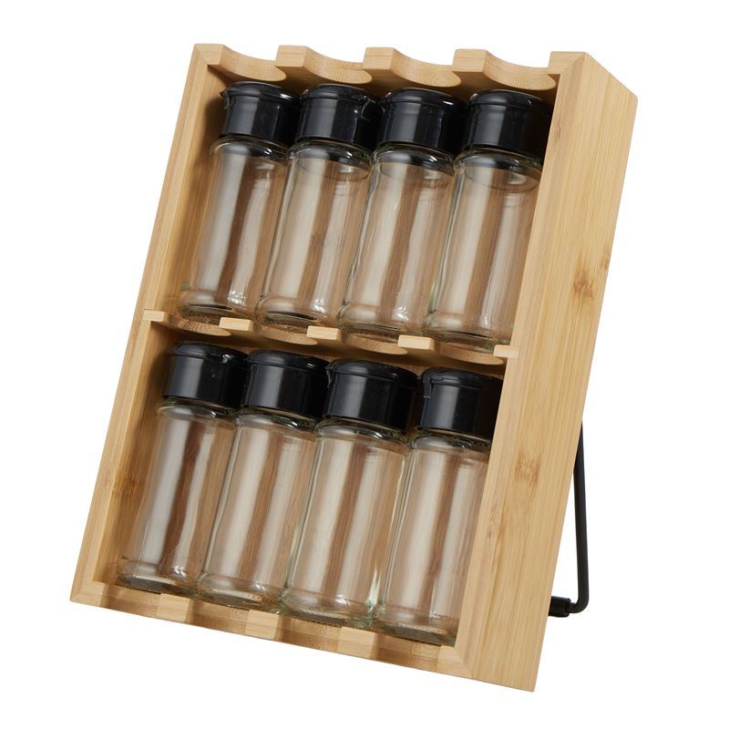 Set of glass spice jars with black lids in a wooden holder on a white background