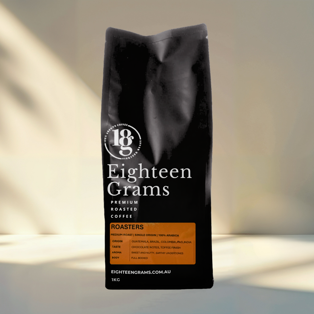 Black coffee bag labeled 'Eighteen Grams' on a neutral background. Roasters Blend – Medium Roast Coffee Beans 1kg